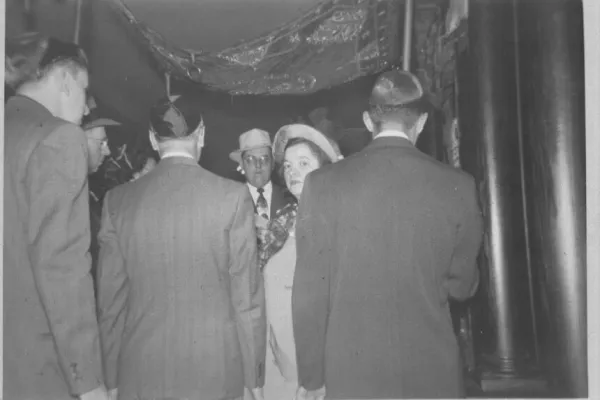 A couple standing under the chuppah during a Jewish wedding ceremony, surrounded by guests