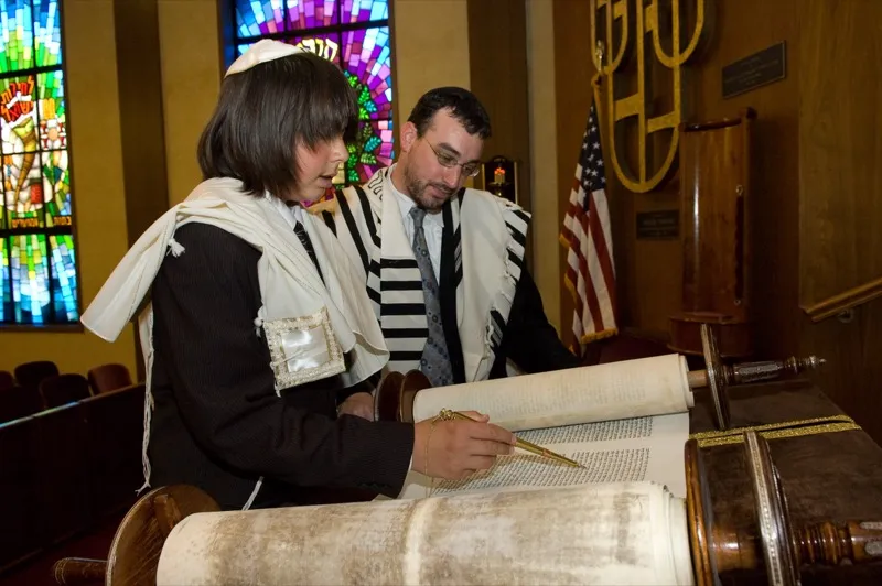 A young person reading from the Torah scroll during a Bar Mitzvah ceremony