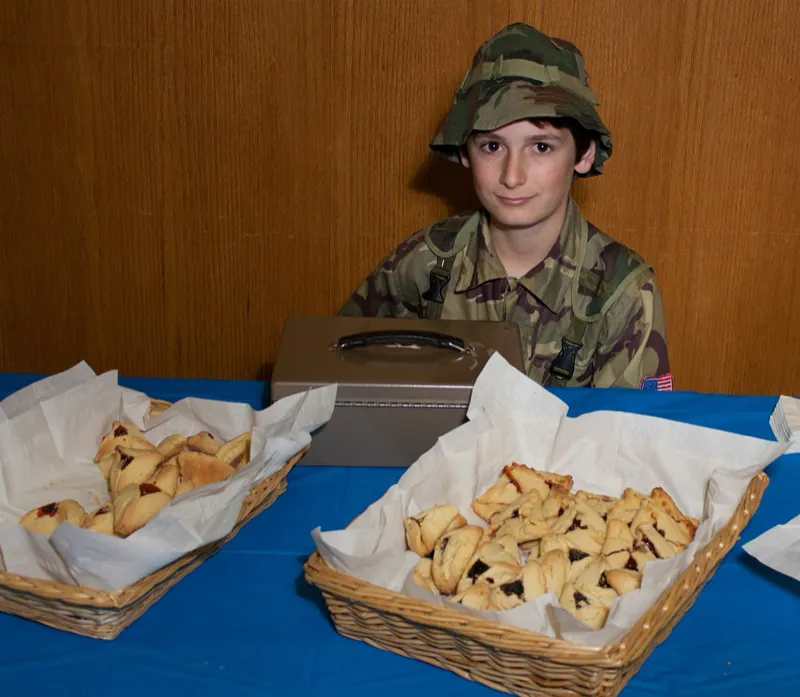 Freshly baked hamantaschen cookies with various fillings arranged on a baking sheet