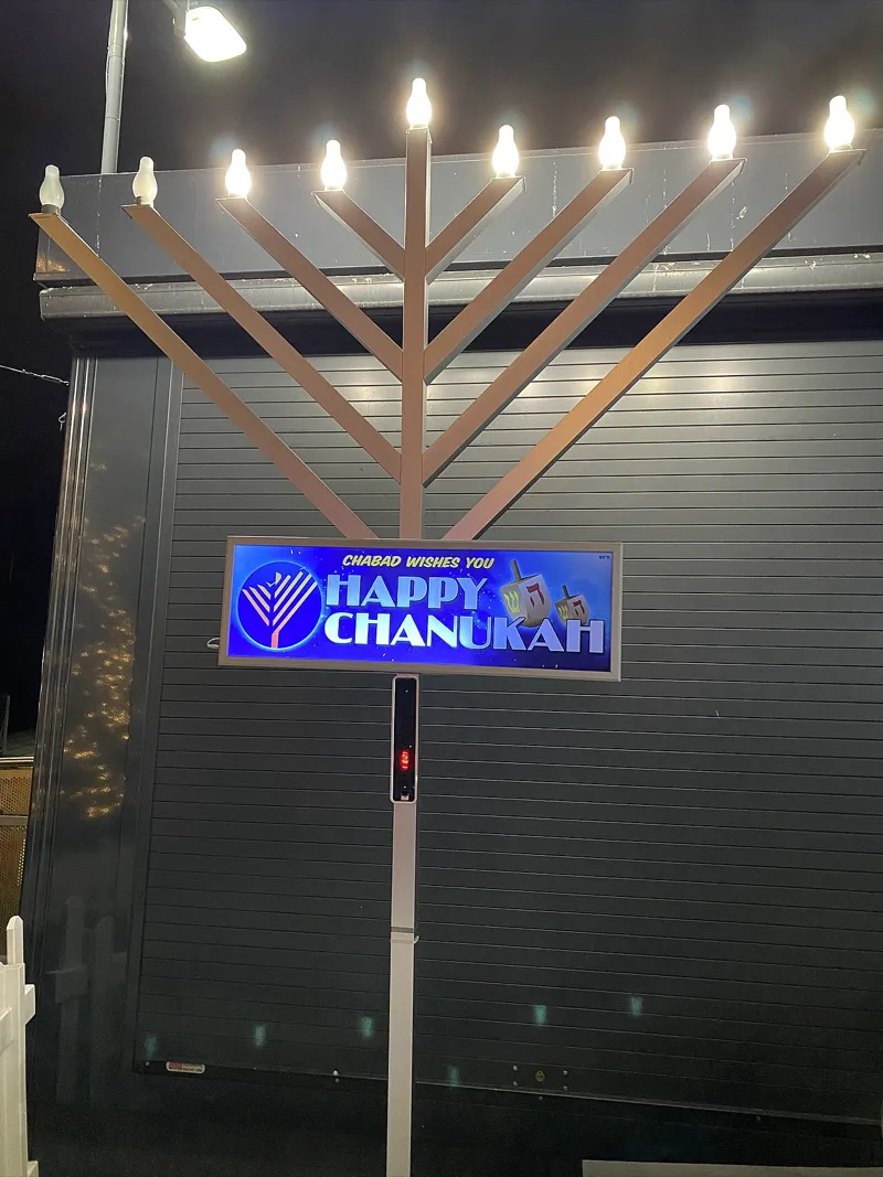 A fully lit Hanukkah menorah with nine candles glowing in a window