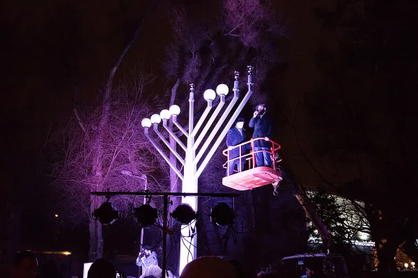A family gathered around a lit menorah singing Hanukkah songs