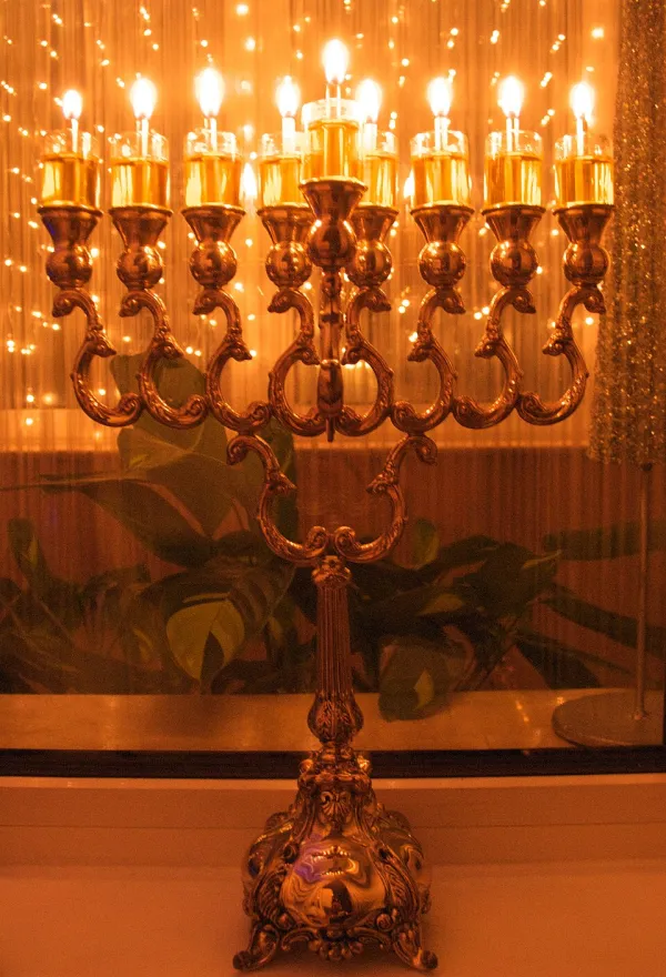 A family lighting a Hanukkah menorah by the window