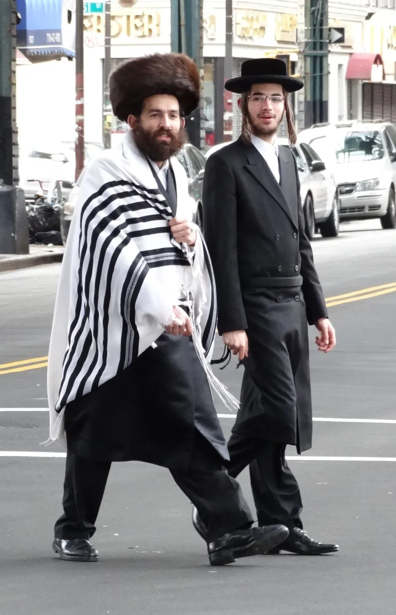 Hasidic Jewish men in traditional black attire walking through their neighborhood