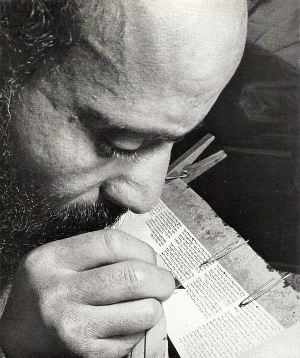 A sofer (scribe) carefully writing Hebrew letters on a Torah scroll