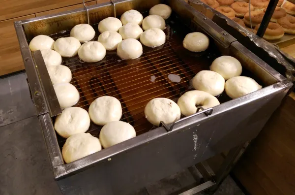 Sufganiyot (jelly doughnuts) and donuts being deep-fried in oil at a Jerusalem bakery for Hanukkah