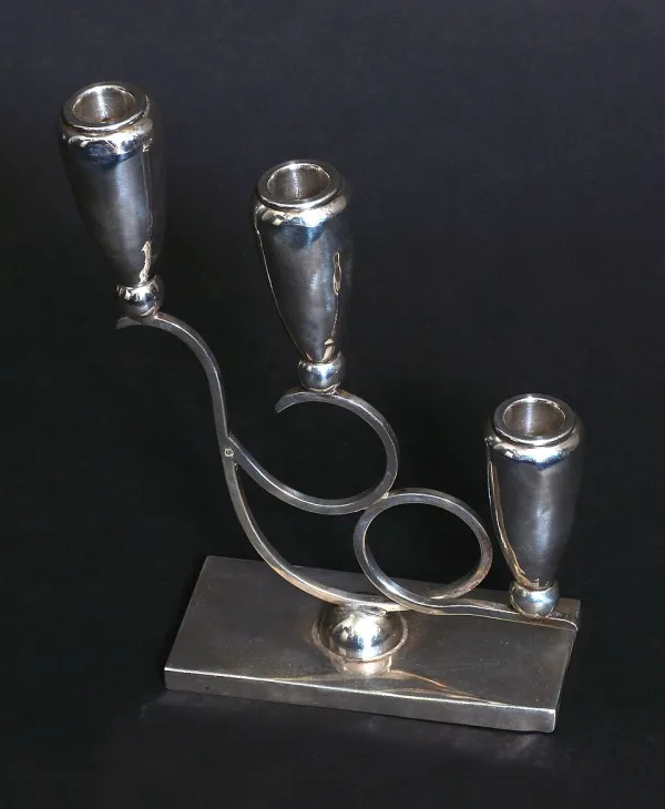 Multiple Shabbat candles lit in a row of silver candlesticks