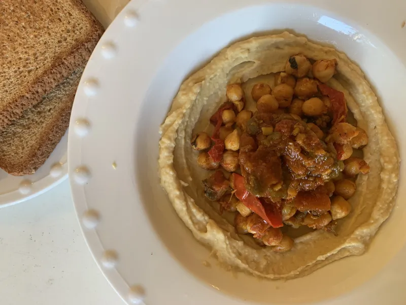 Plate of creamy hummus topped with olive oil, chickpeas, and served with fresh pita