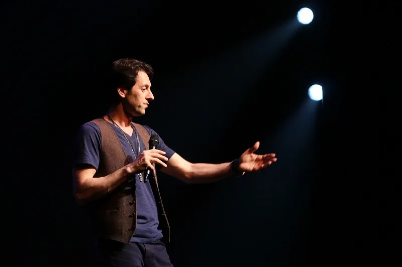 A vintage microphone on a stand-up comedy stage with a spotlight