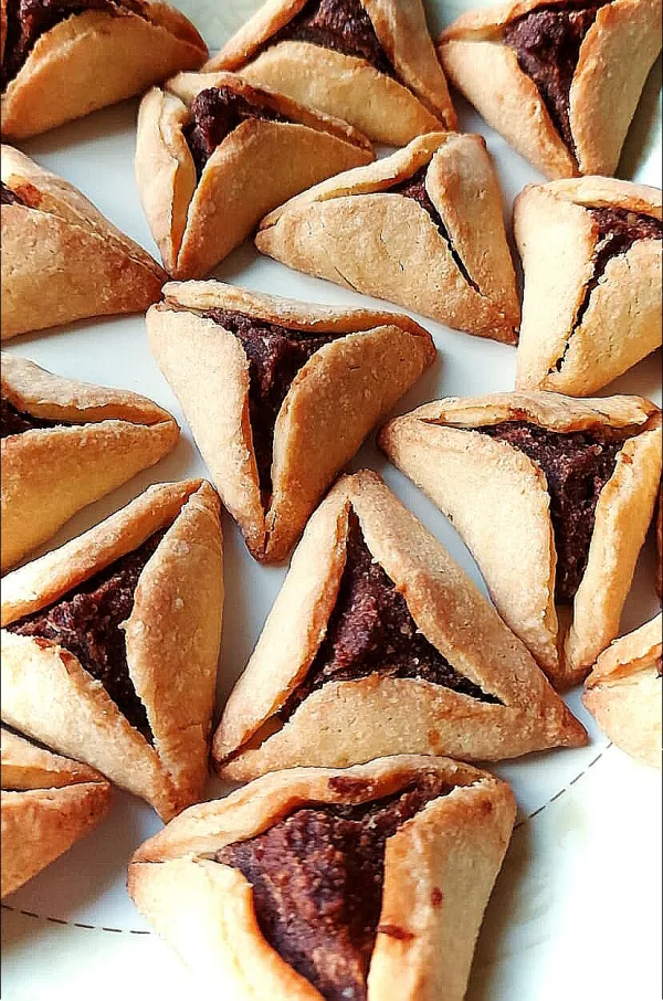 A glass of malabi topped with rose syrup and crushed pistachios