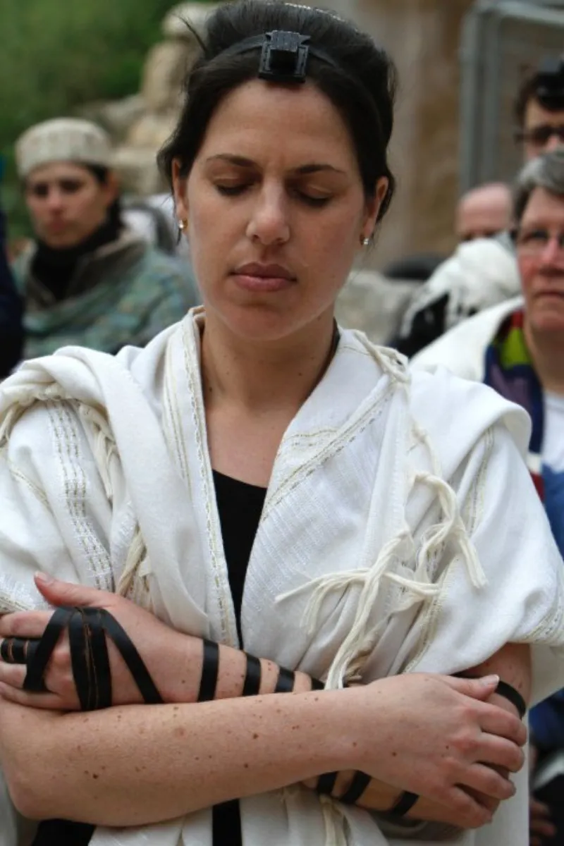 A woman reading from the Torah scroll during a synagogue service