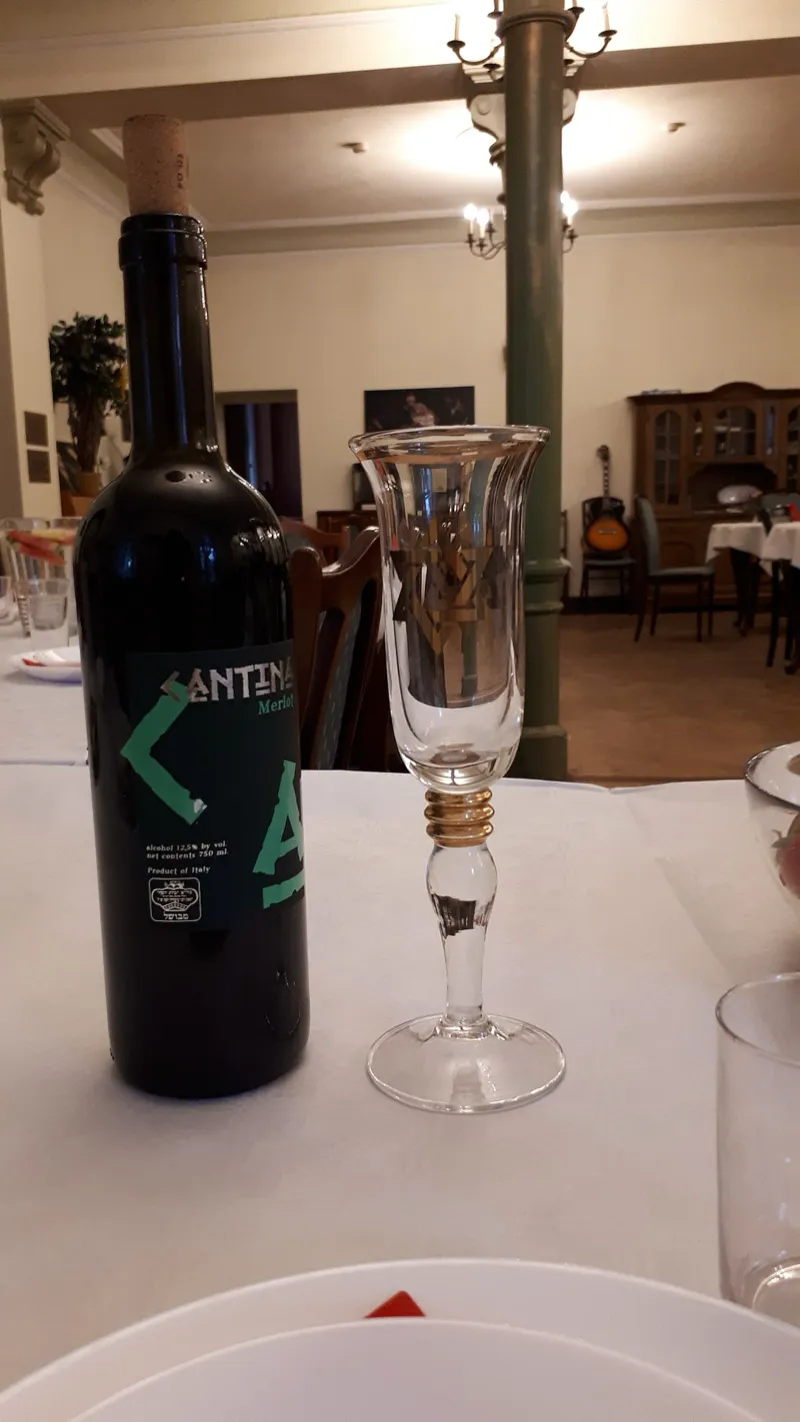 A silver kiddush cup filled with red wine on a Shabbat table