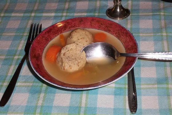 Matzo balls in broth, showing the traditional round dumpling shape