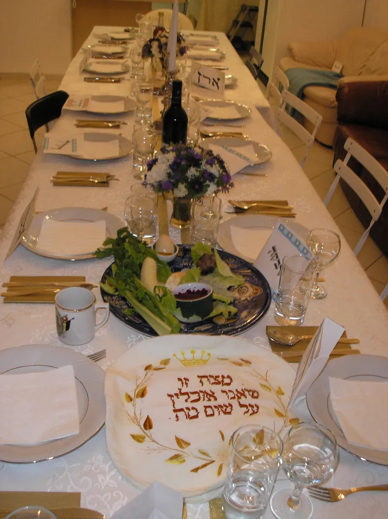 A traditional Passover Seder table with a Seder plate, matzah, wine, and Haggadah
