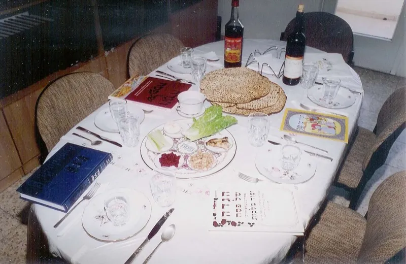 A beautifully arranged seder table with matzah, wine, a seder plate, and Haggadot
