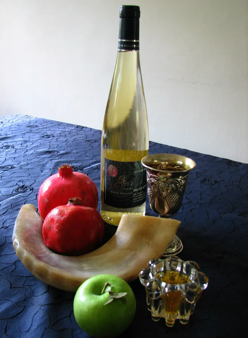 A shofar, apples, honey, and pomegranates arranged for Rosh Hashanah