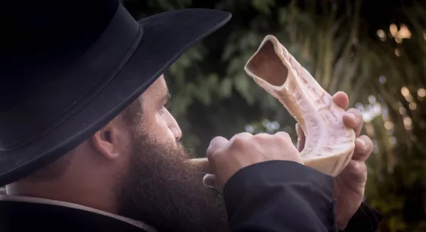 A person blowing the shofar in a synagogue during Rosh Hashanah services