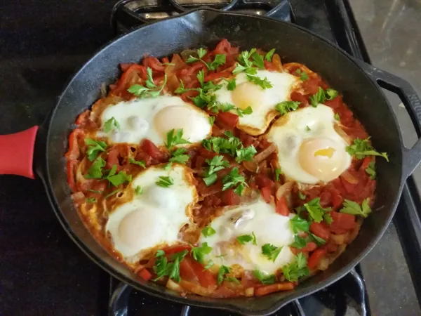 A pan of shakshuka — eggs poached in spiced tomato sauce, a beloved Sephardic and Israeli dish