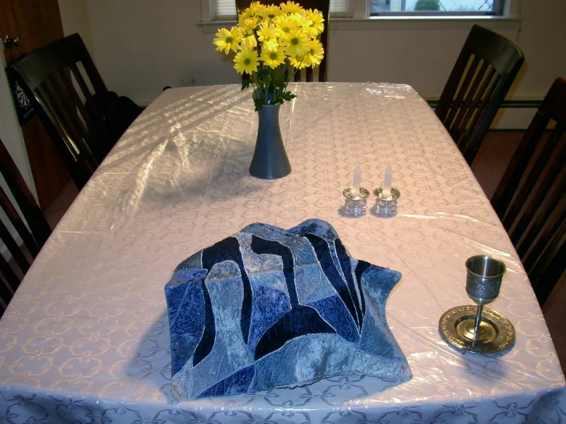 A beautifully set Shabbat table with lit candles, challah bread, and wine