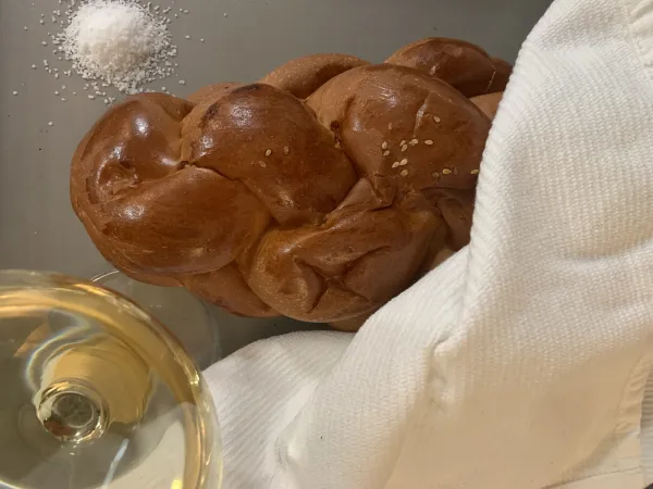 A family performing havdalah with a braided candle, wine cup, and spice box