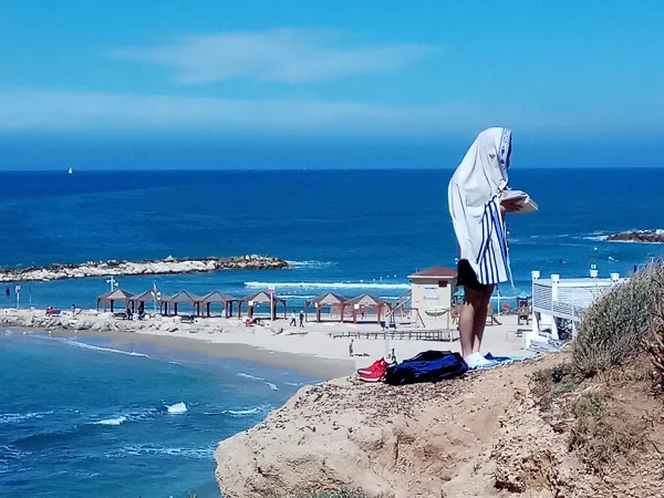 Jewish men wrapped in tallitot during morning prayer on the beach in Tel Aviv