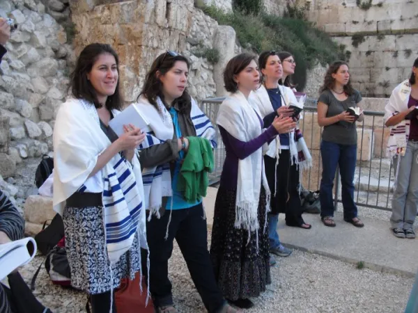 Women praying together with prayer shawls at a religious gathering